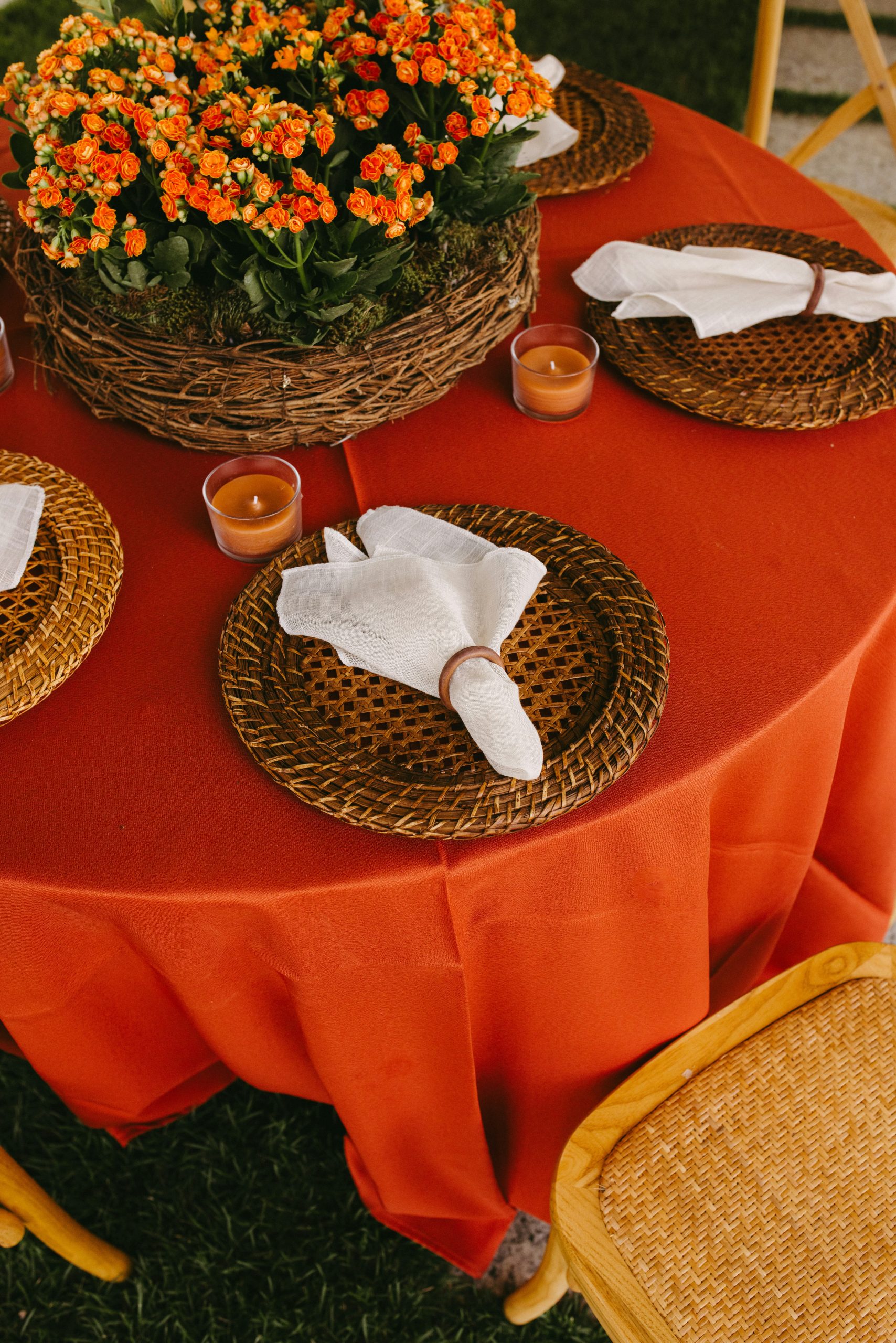 Red table setting with orange flowers and woven placemats