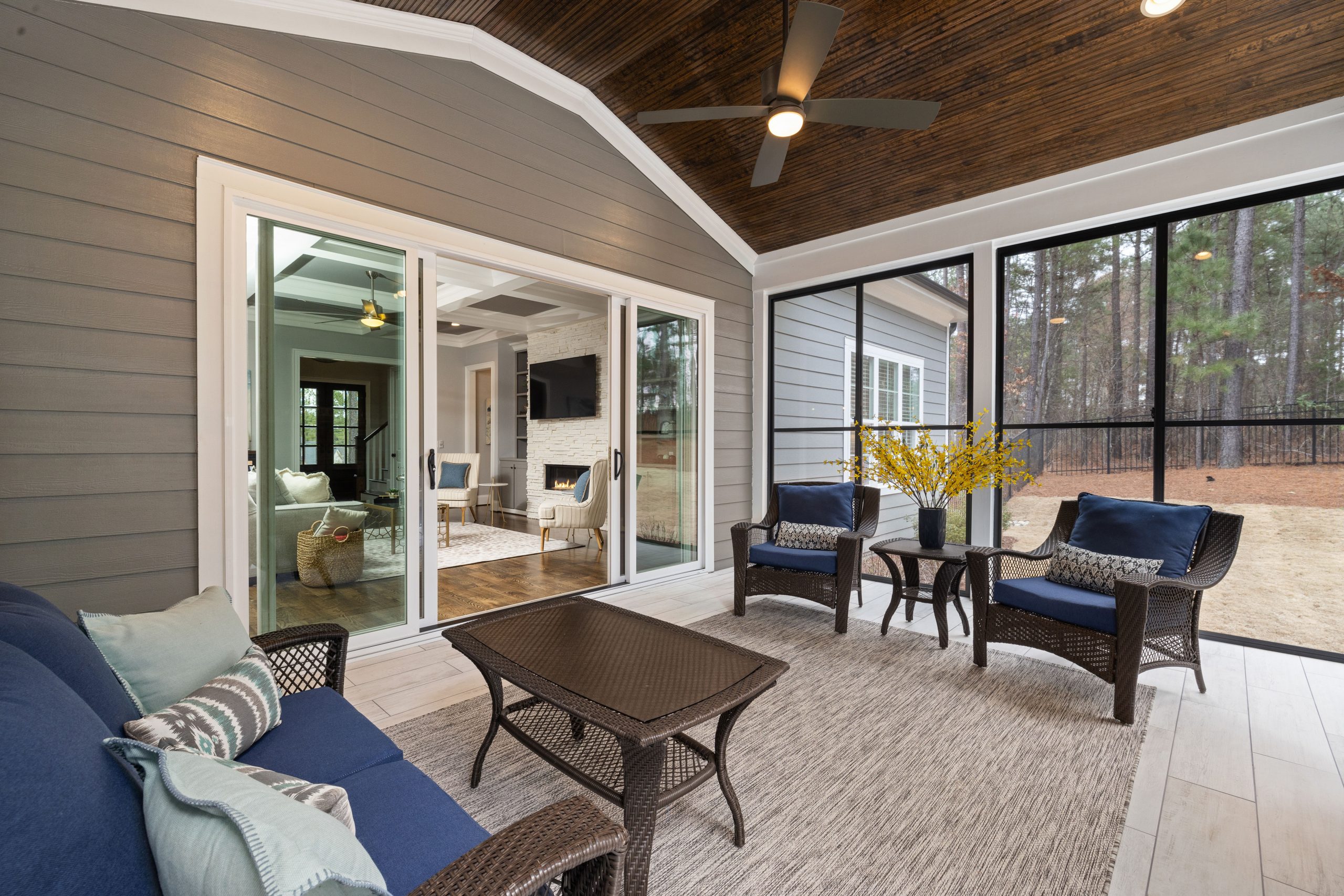 Sunlit enclosed porch with wicker furniture and views of lush greenery.