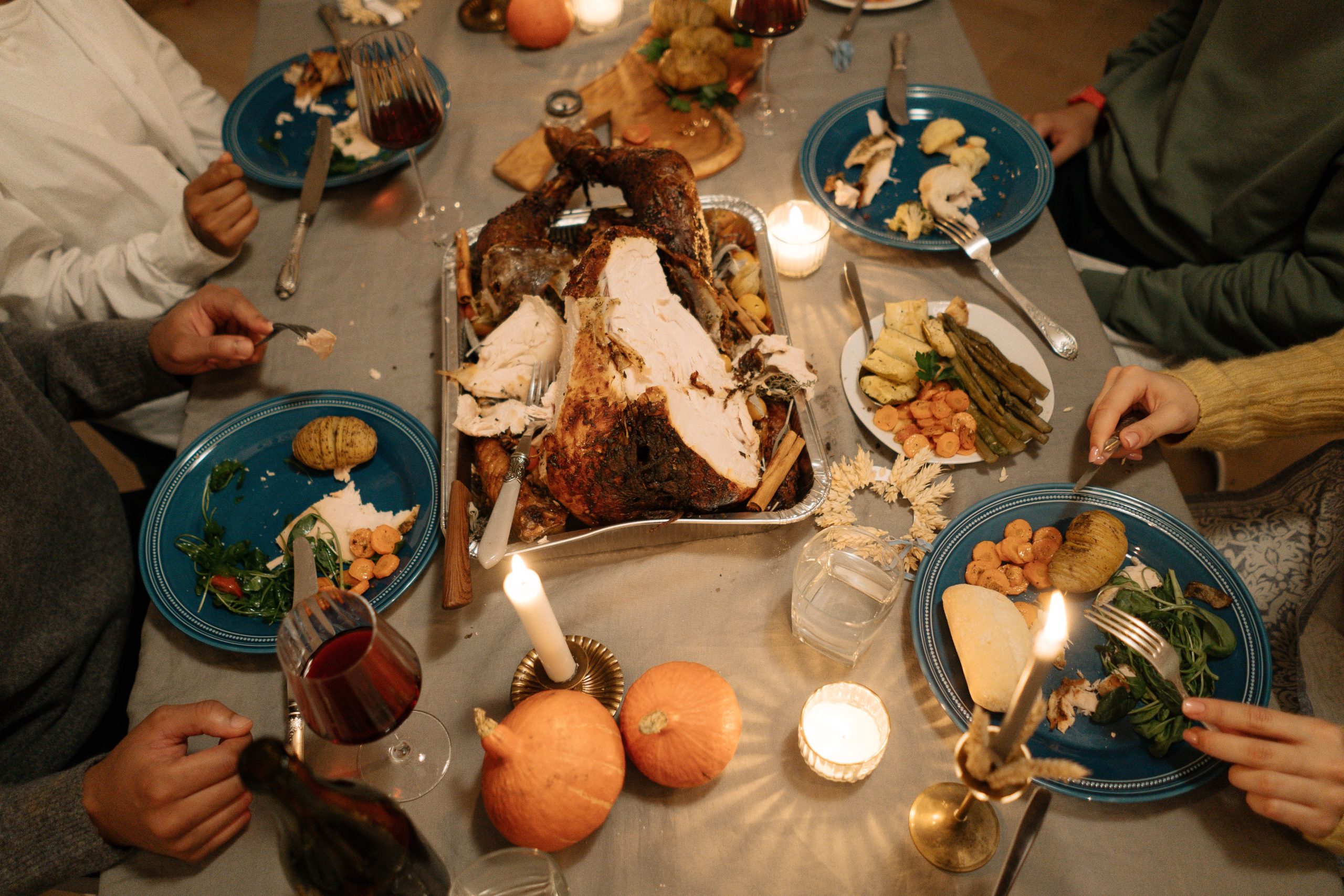 Top view of a cozy holiday dinner with a roasted turkey centerpiece and festive table setting.