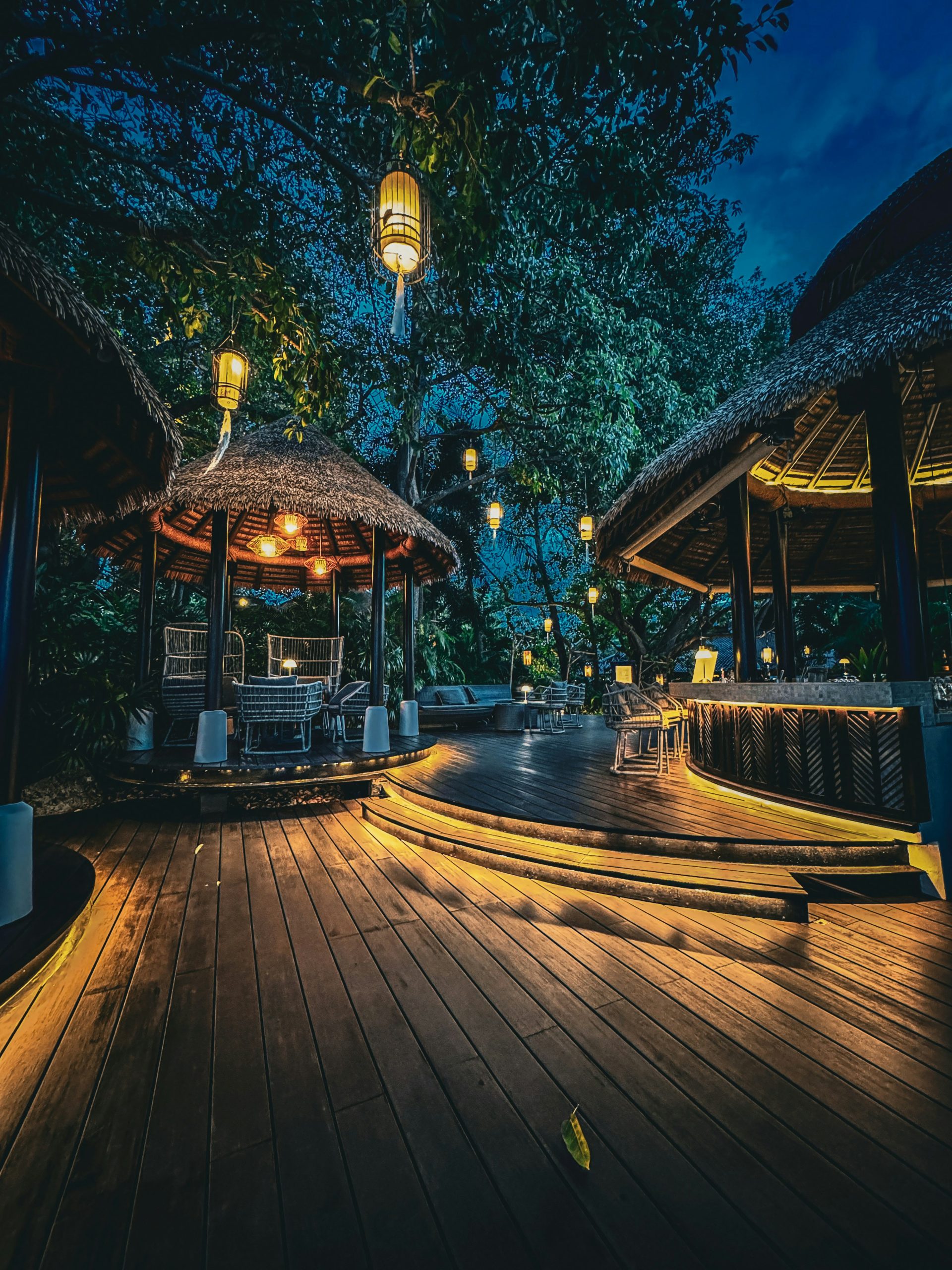 Tropical resort at night with illuminated gazebos and wooden deck