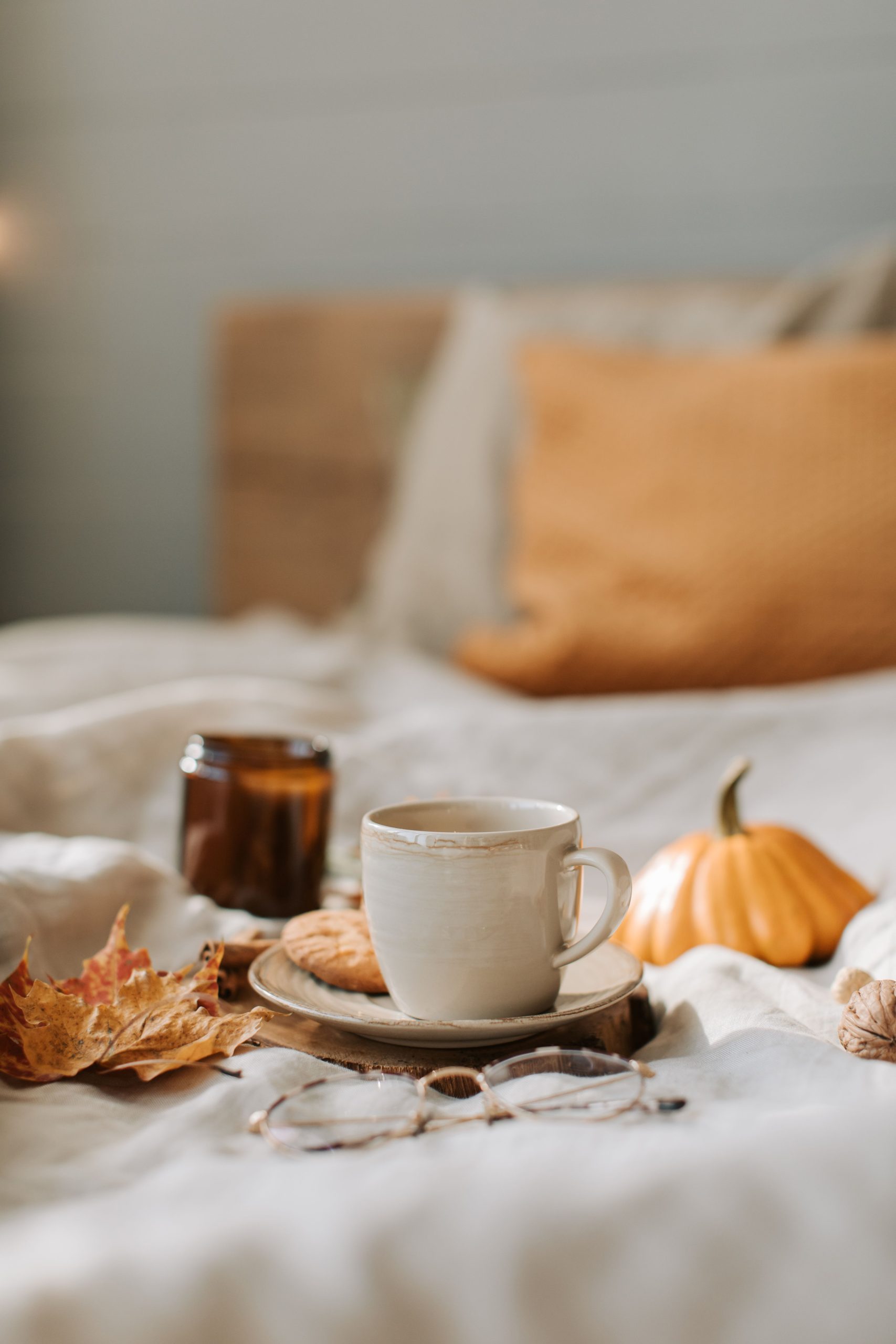 Warm autumn vibes with coffee and decor on a cozy bed for seasonal comfort.