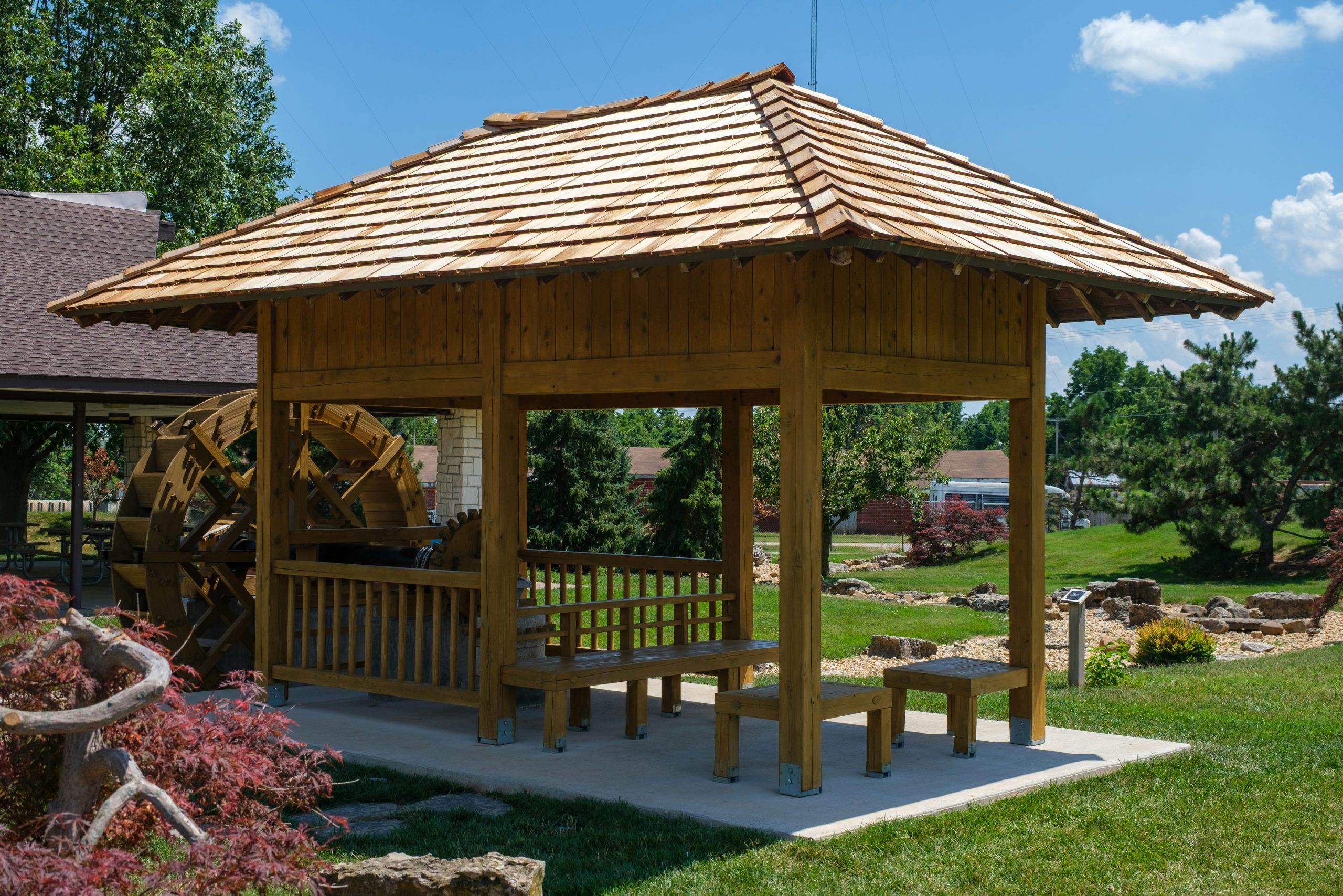 Wooden gazebo with seating in a sunny garden