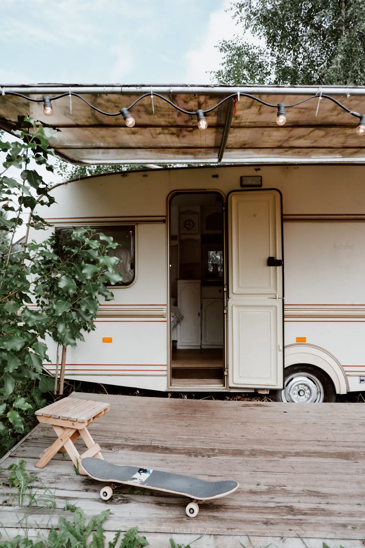 A comfortable caravan with an inviting deck, complemented by a skateboard and stool for a relaxed outdoor vibe.