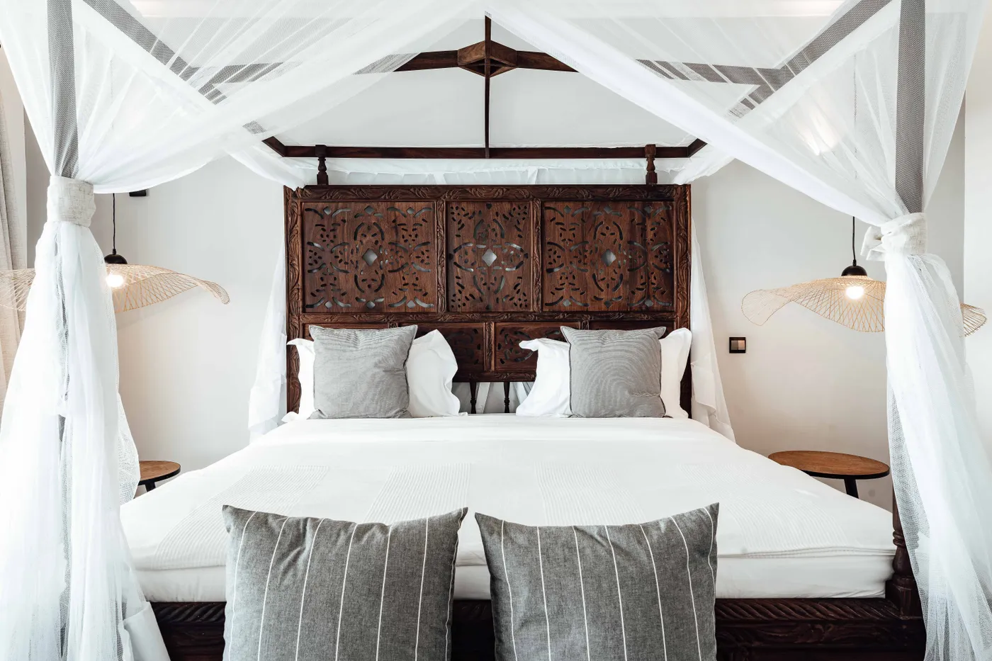 A cozy and contemporary bedroom with a stylish canopy bed featuring carved wood details.