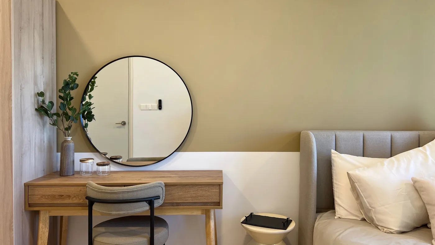 A cozy bedroom featuring a wooden vanity, mirror, and soft textiles, perfect for modern interior design.