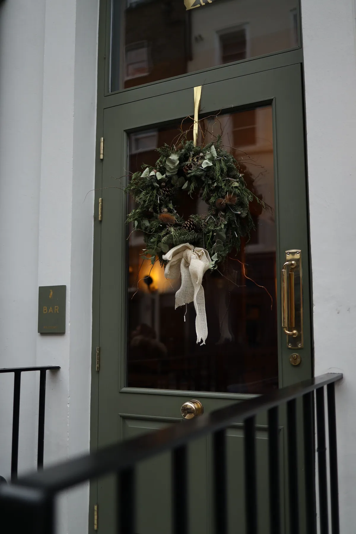 A festive holiday wreath adorns a green exterior door, adding charm and warmth to the entrance.