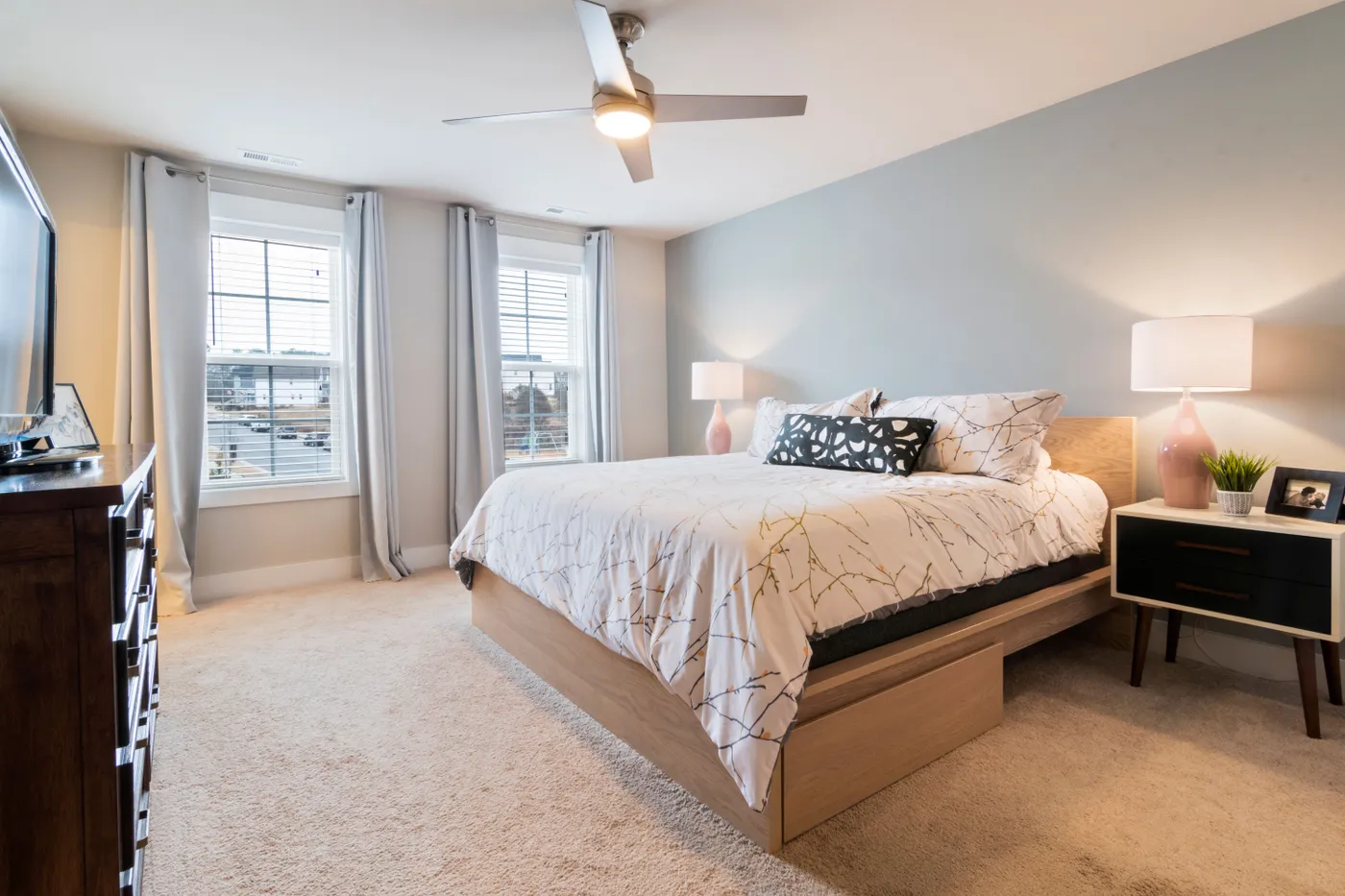 A minimalist bedroom with modern decor, soft lighting, and natural light from large windows.
