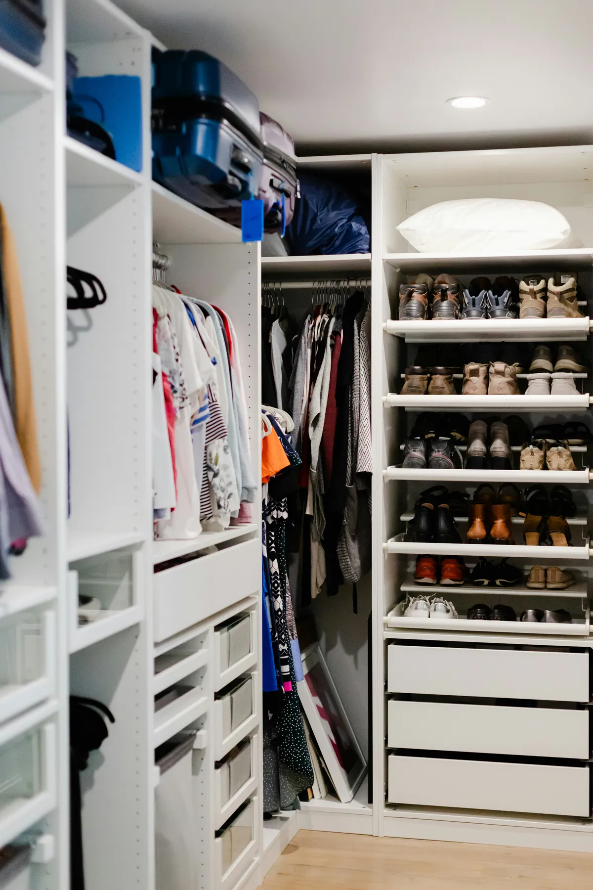 A modern, white closet with open shelving, drawers, and a rack for clothes & footwears.