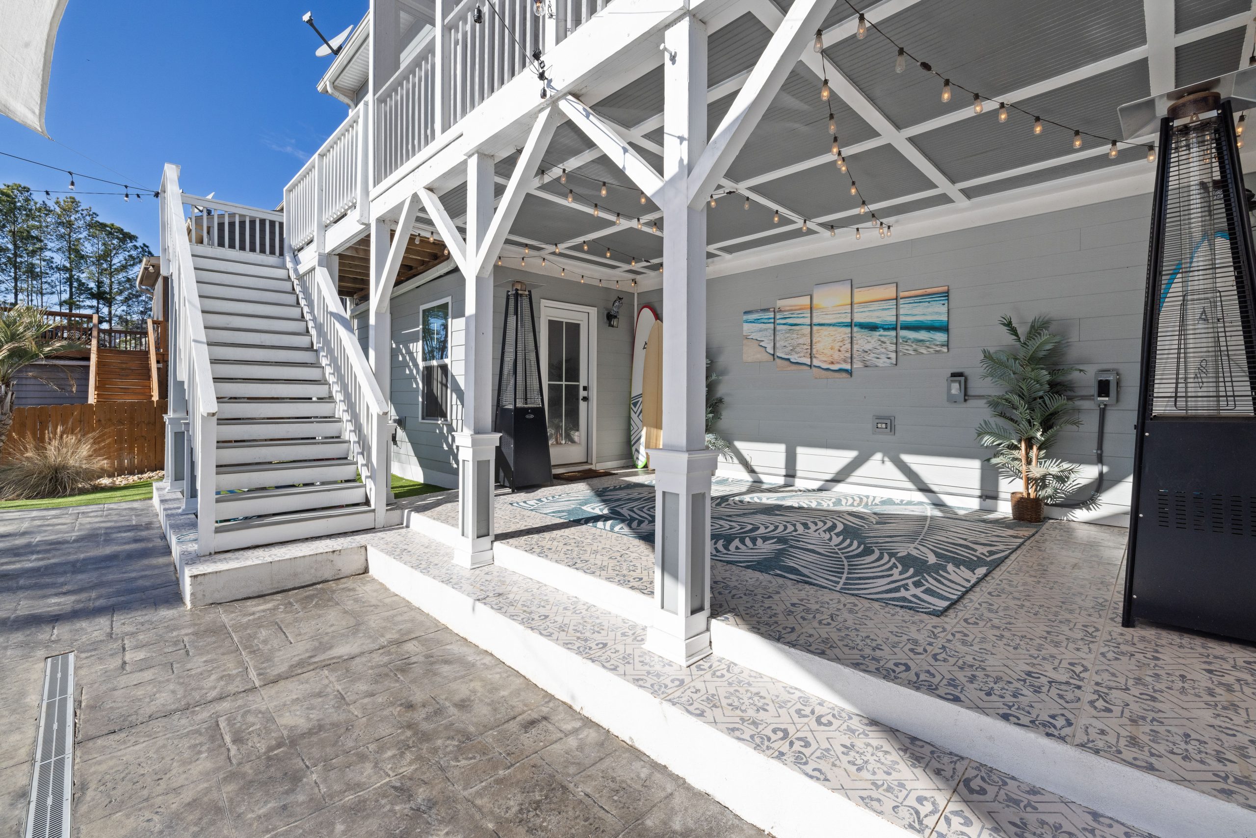 A stylish outdoor patio featuring string lights, surfboards, and sea-themed art, creating a coastal ambiance.