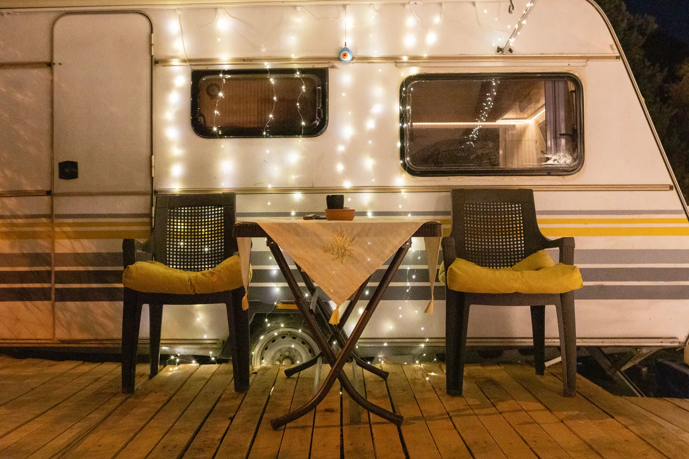A warmly lit camper van setup with chairs and fairy lights, perfect for a relaxing night outdoors.