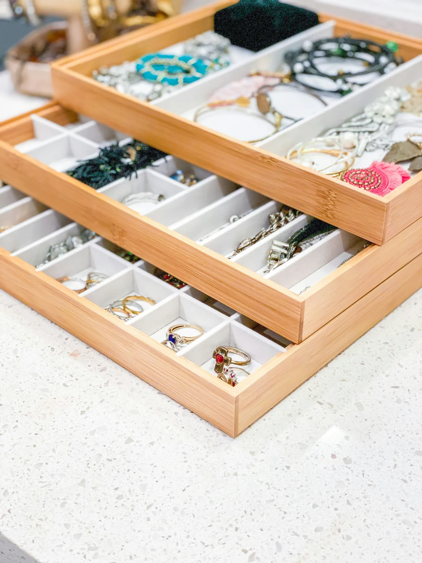 A wooden compartmentalized tray keeps rings, bracelets, and earrings neatly organized and easy to find.