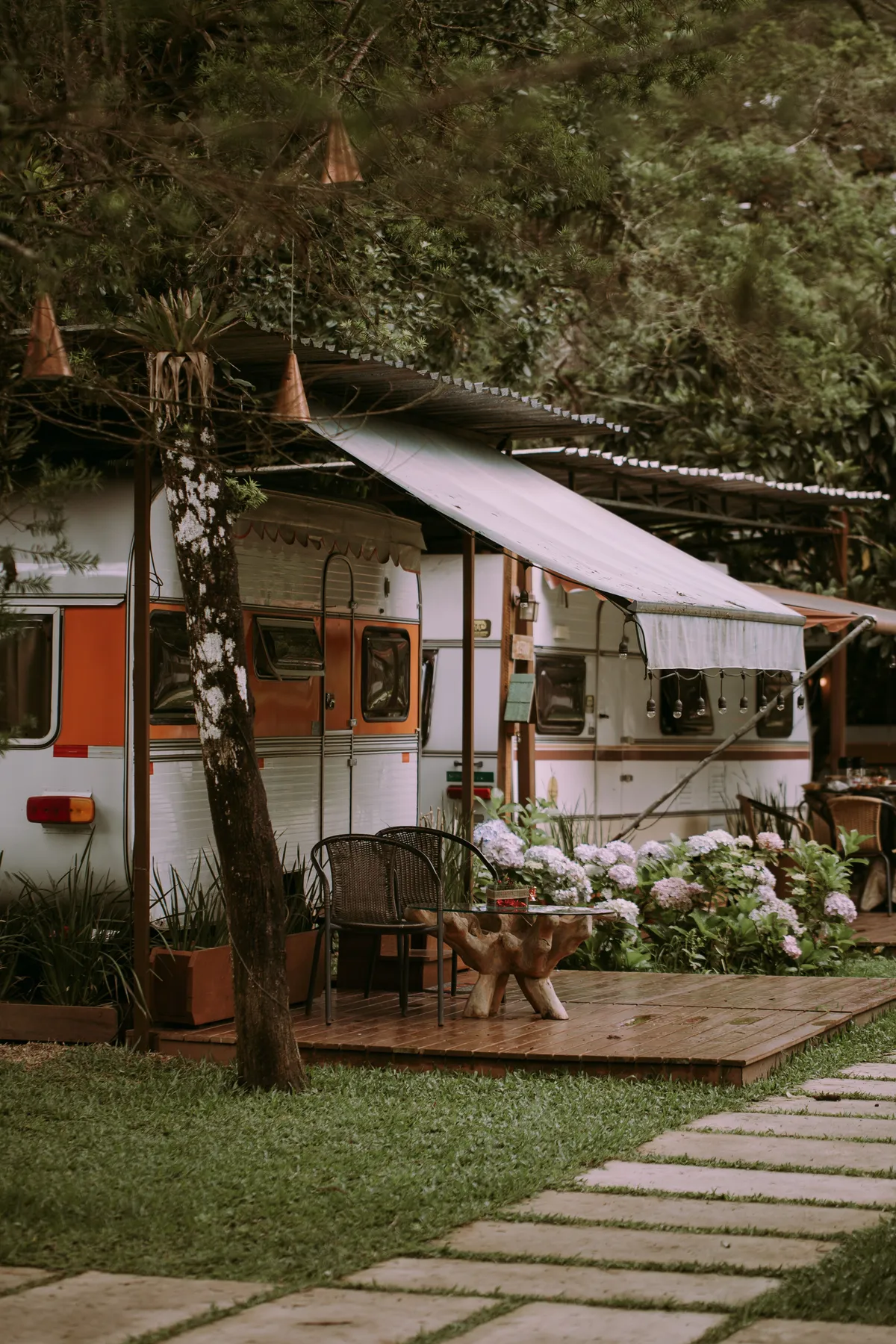 Charming outdoor caravan setup with a rustic awning and lush greenery for a perfect summer camping vibe.