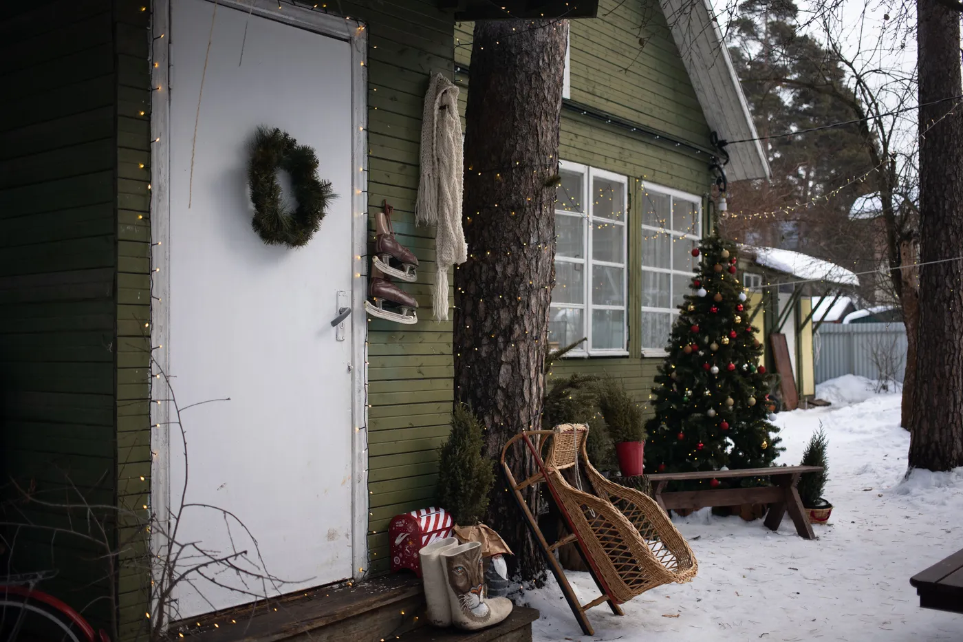 Charming winter cabin decorated with a Christmas tree, wreath, and festive lights.