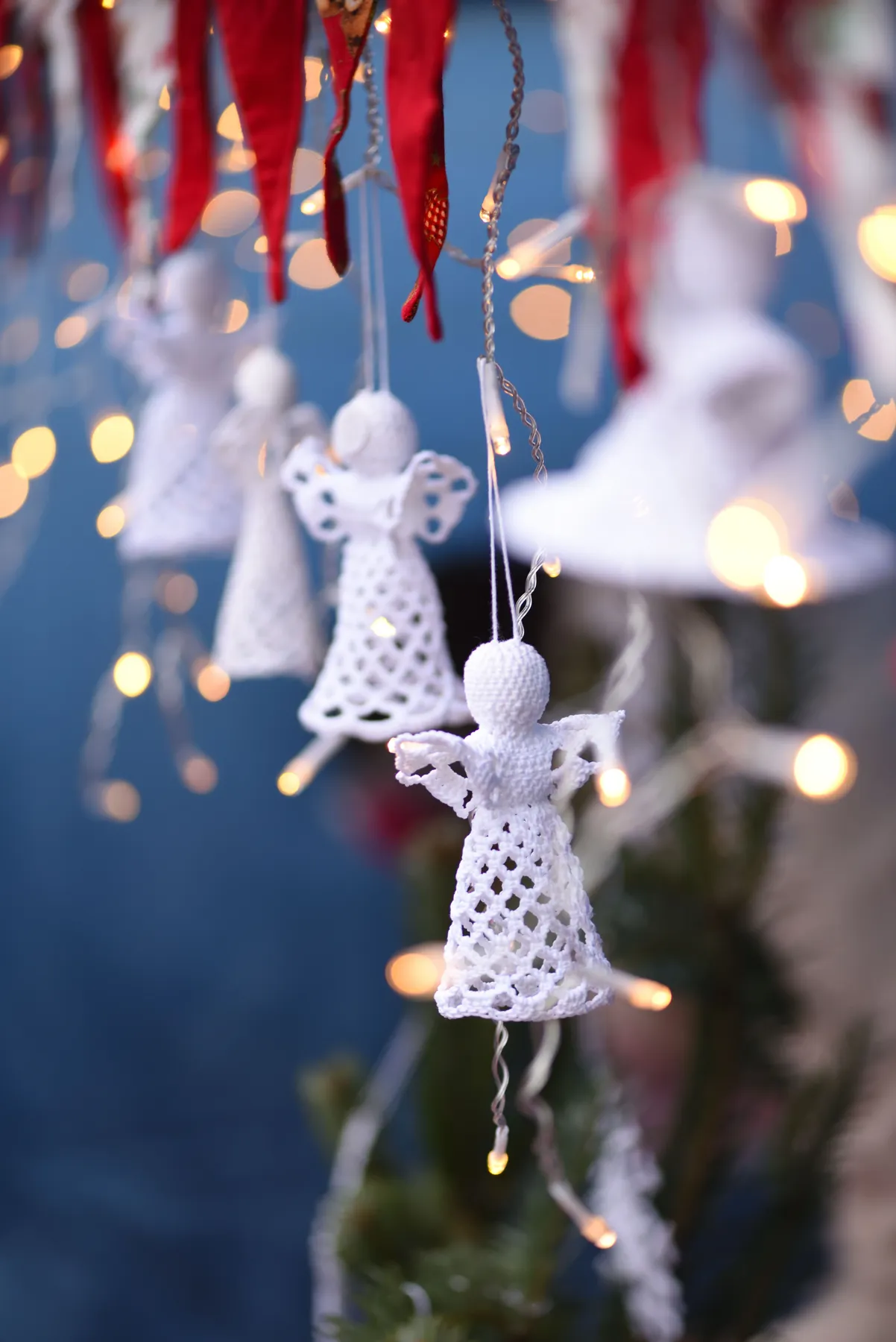 Close-up of handmade crochet angels hanging at a festive Christmas market in Hannover, Germany.
