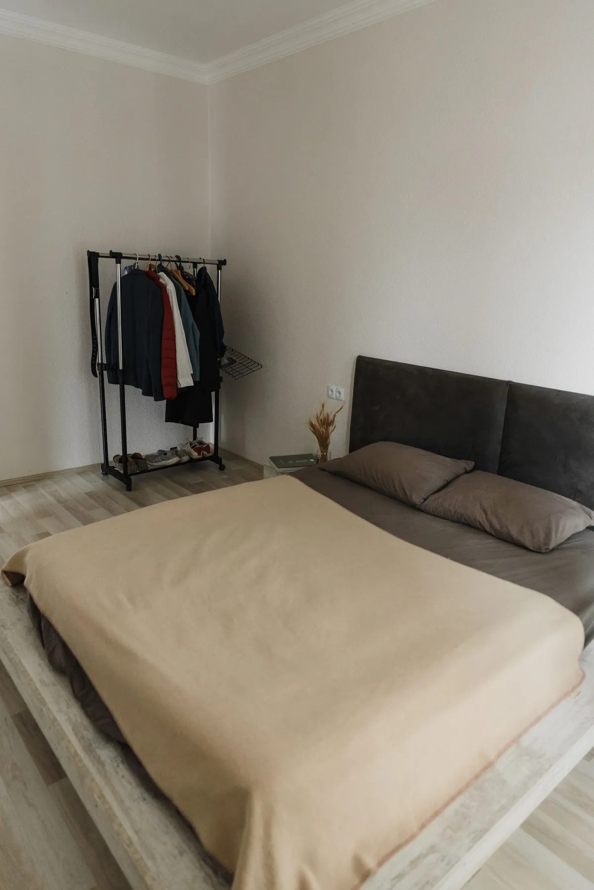 Cozy minimalist bedroom featuring a bed and a clothes rack for a simple living vibe.