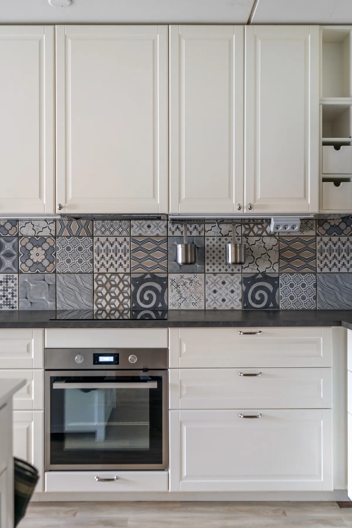 Elegant kitchen design featuring white cabinets and a patterned mosaic tile backsplash.
