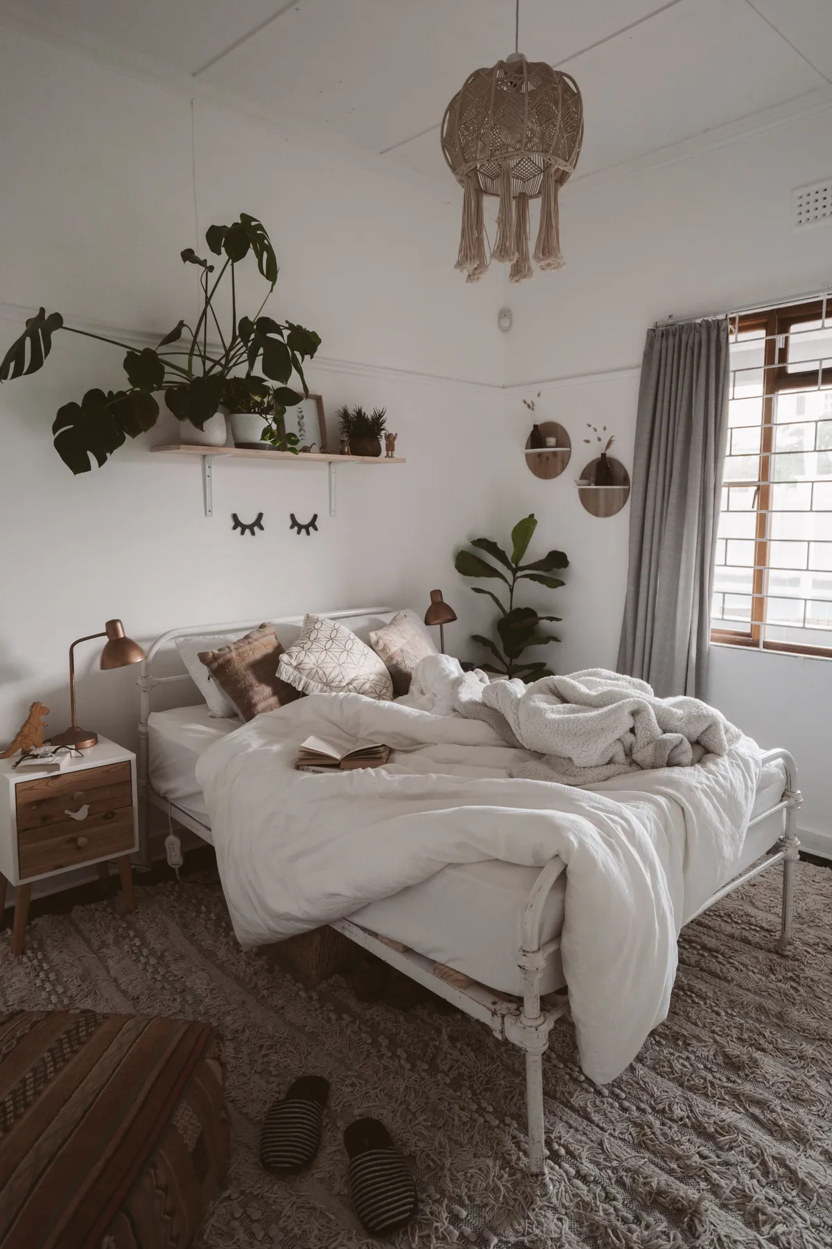 Inviting bedroom with cozy Scandinavian decor, featuring a lush indoor plant and textured bedding.