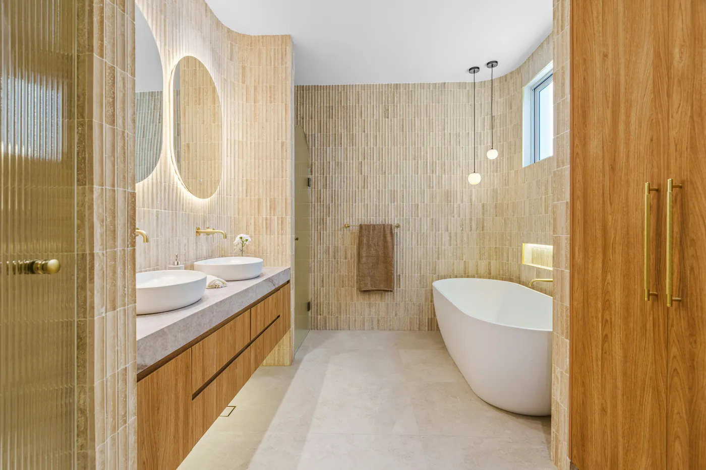 Modern bathroom with double sinks, freestanding tub, and wooden accents