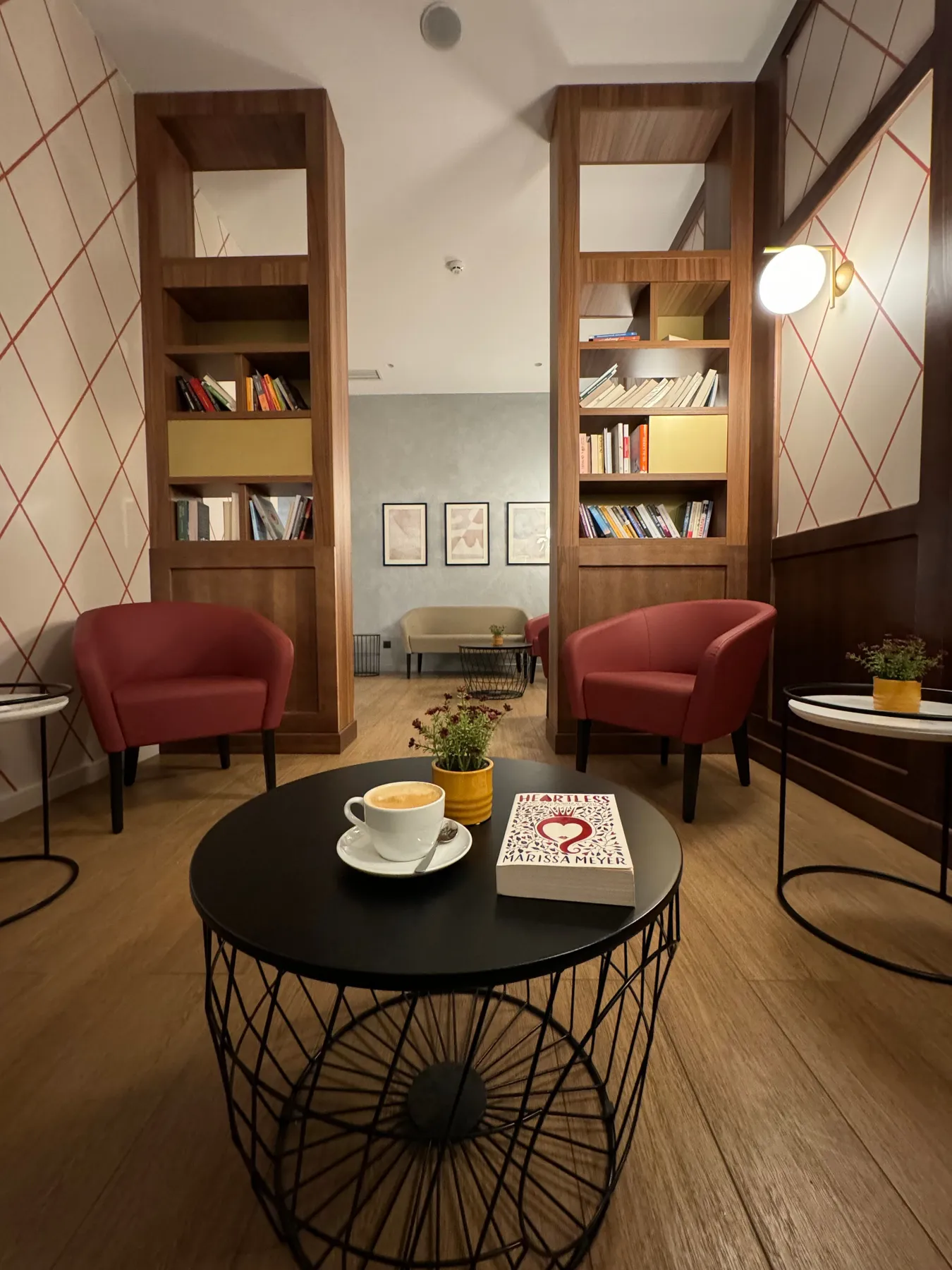 Modern reading room with red chairs, coffee table, and bookshelves.