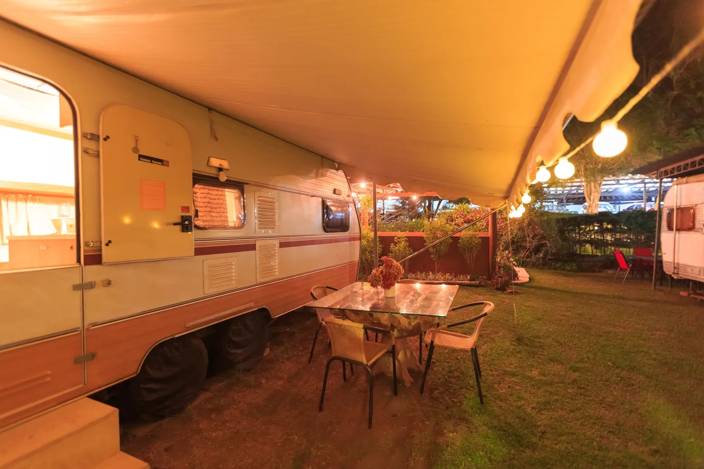 Relaxing night scene of an outdoor RV setup with ambient lighting and a dining table.
