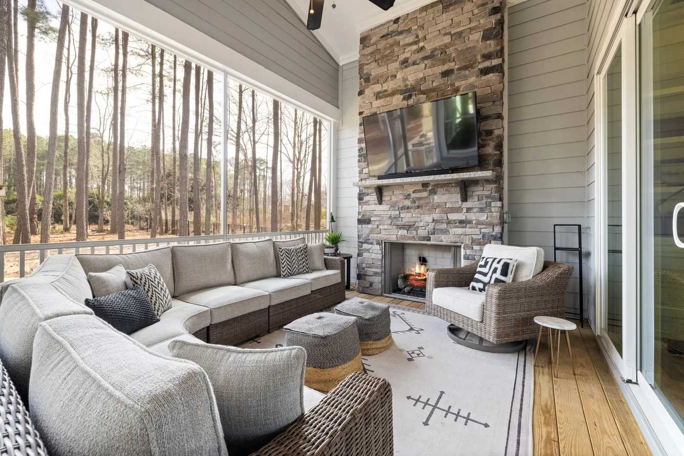 Spacious outdoor patio featuring a stone fireplace, modern furniture, and serene forest view.