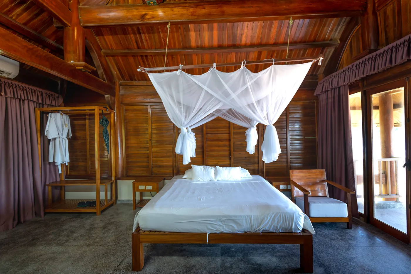 Spacious wooden bedroom featuring a canopy bed and elegant design, perfect for a serene hotel stay.