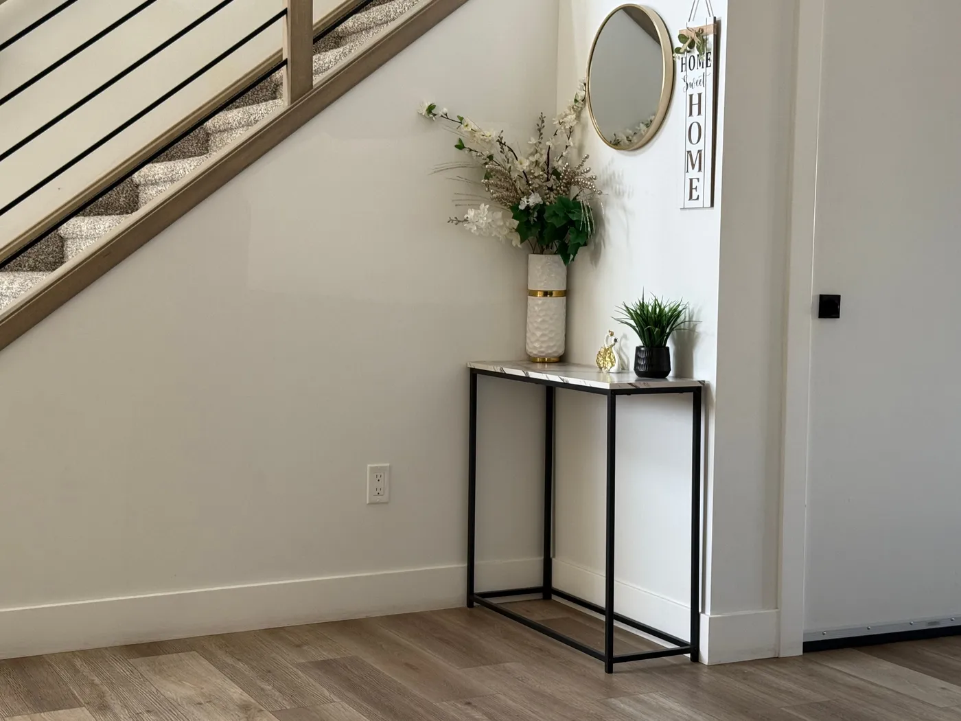 Stylish entryway with minimalist decor, modern staircase, and elegant plants.