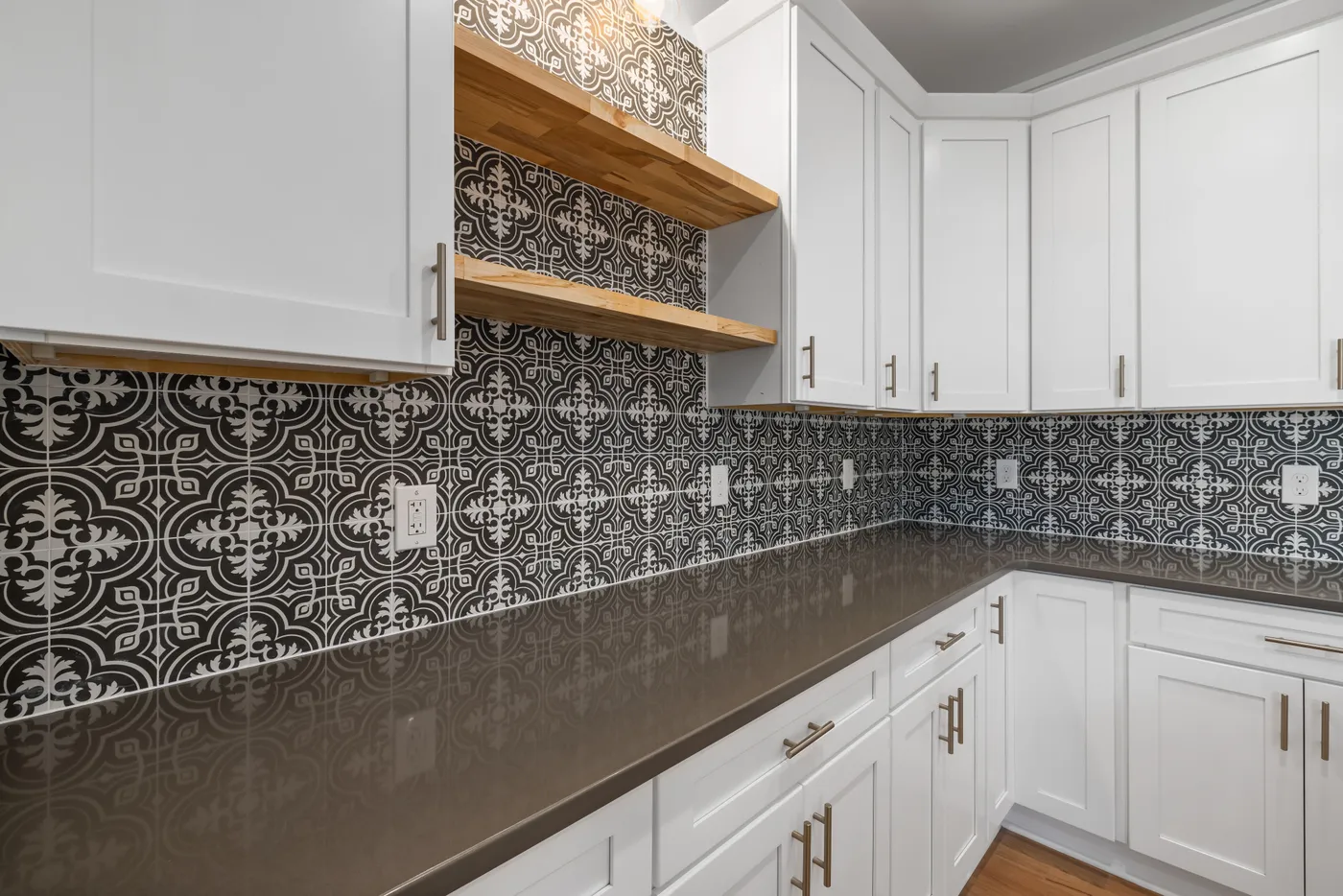Stylish kitchen interior featuring modern white cabinets and geometric patterned tile backsplash.