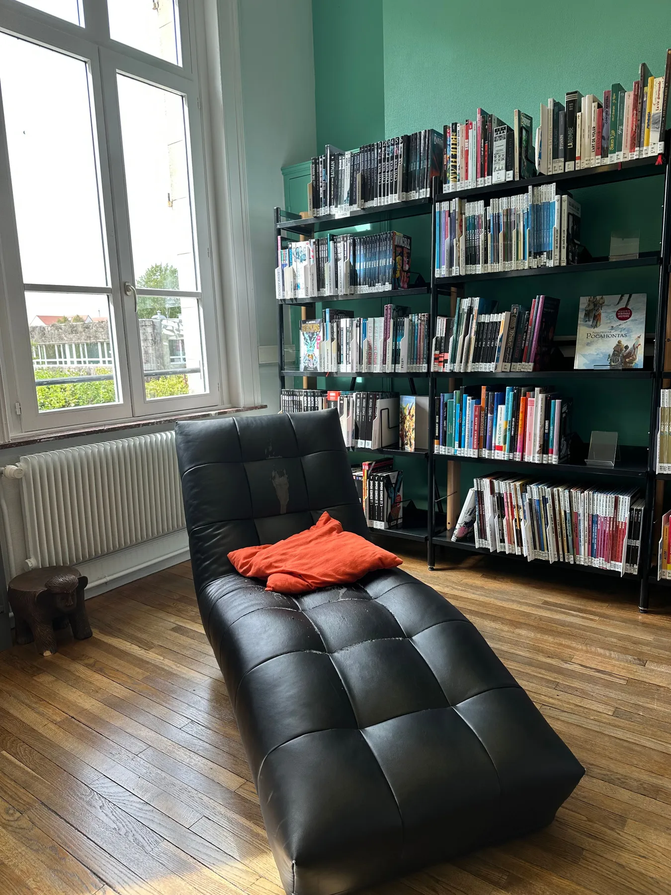 Stylish library interior with bookshelves, a chaise lounge, and natural light.