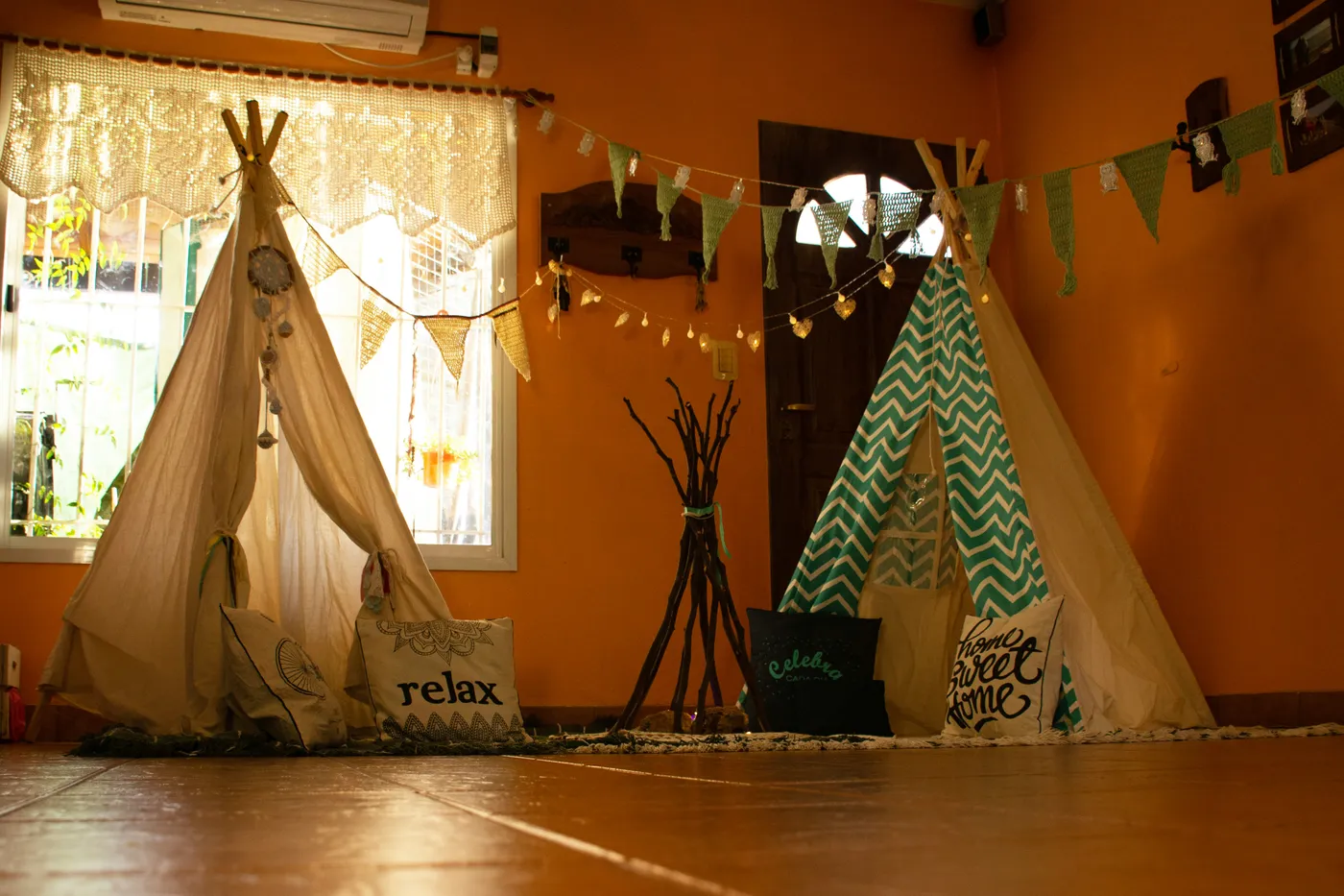 Two fabric play tents with cushions and bunting in an orange room